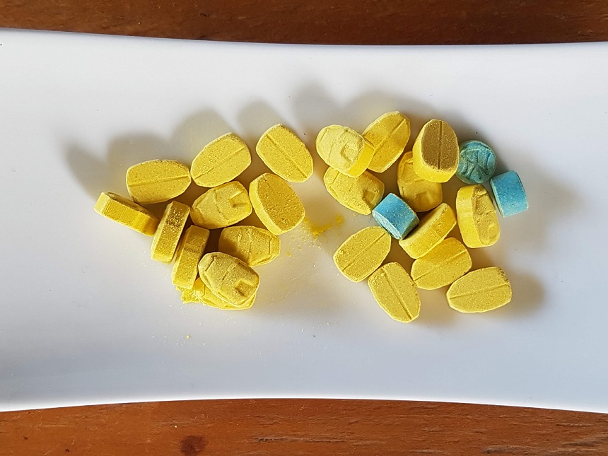 image, large number of yellow pressed MDMA pills in the shape of Iron Man's helmet