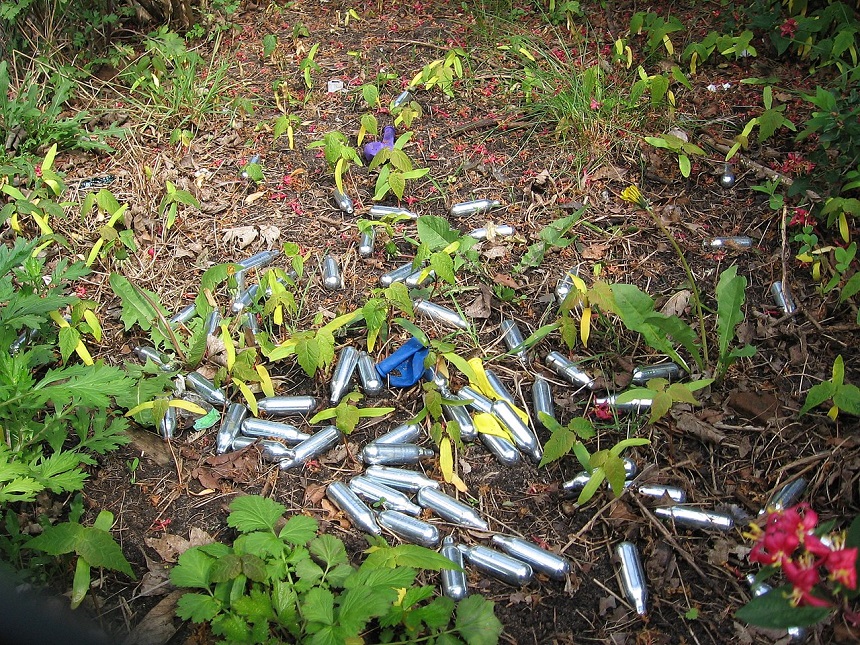 Image showing empty NOS cannisters and balloons in the underbrush after a doof